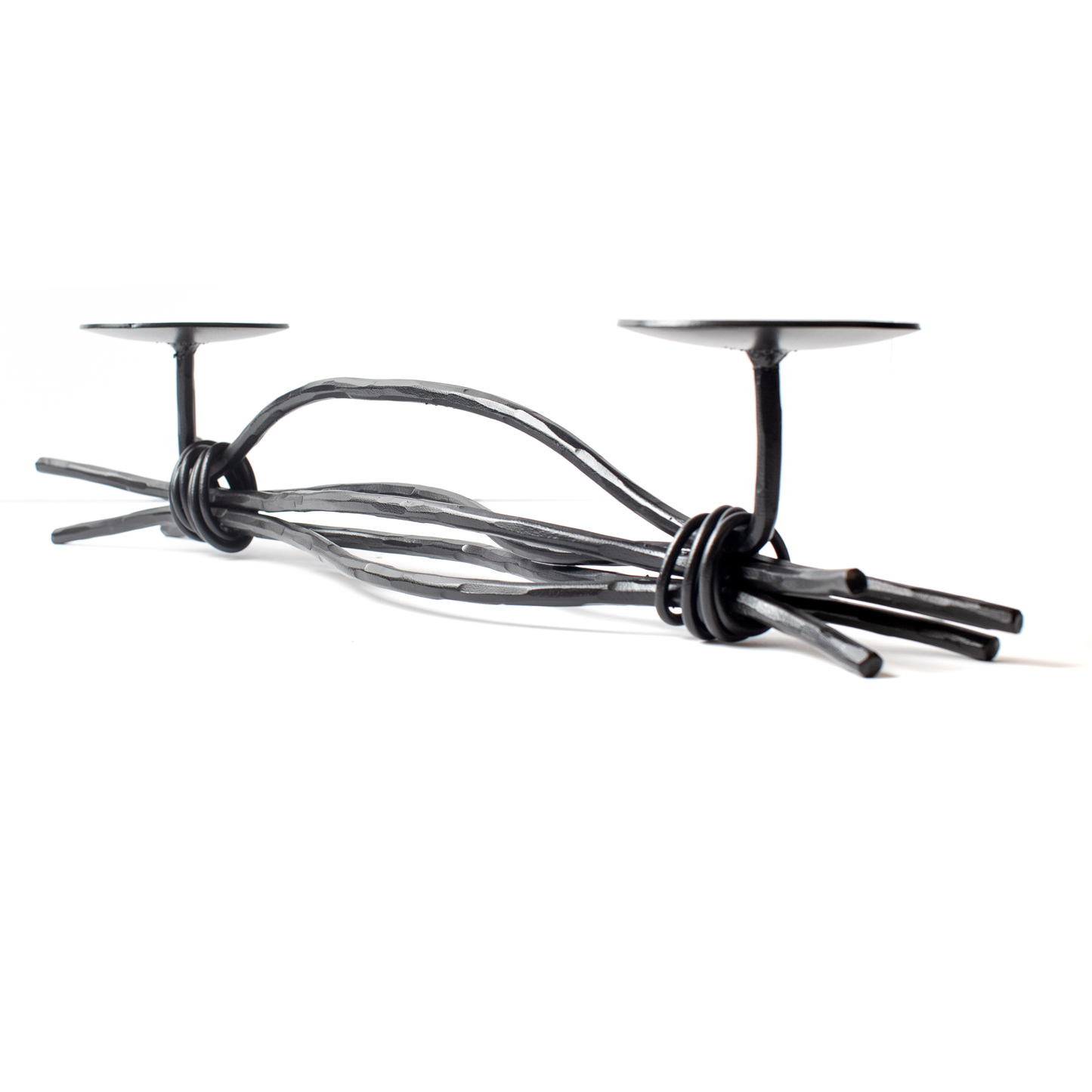An Urban Forge Black River hand-forged iron double candle holder in a black finish. It's pictured against a white backdrop.