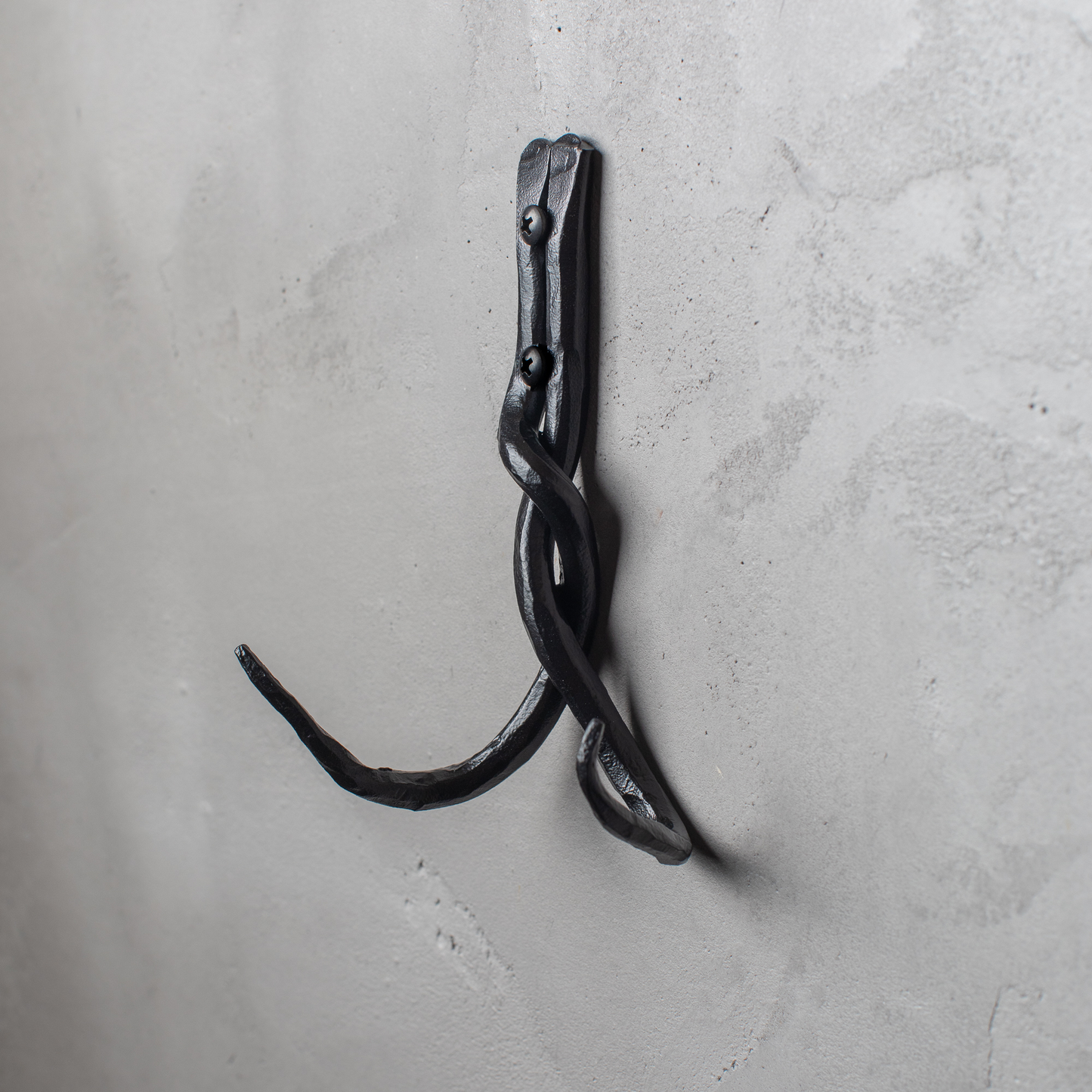 An Urban Forge Black River hand-forged iron double hook in a black finish. The hook is mounted on a gray wall.