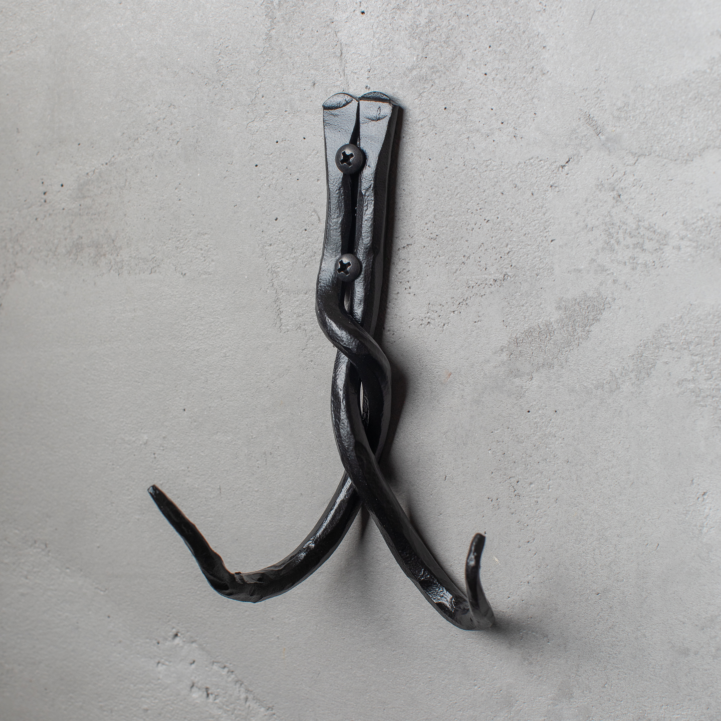 An Urban Forge Black River hand-forged iron double hook in a black finish. The hook is mounted on a gray wall.