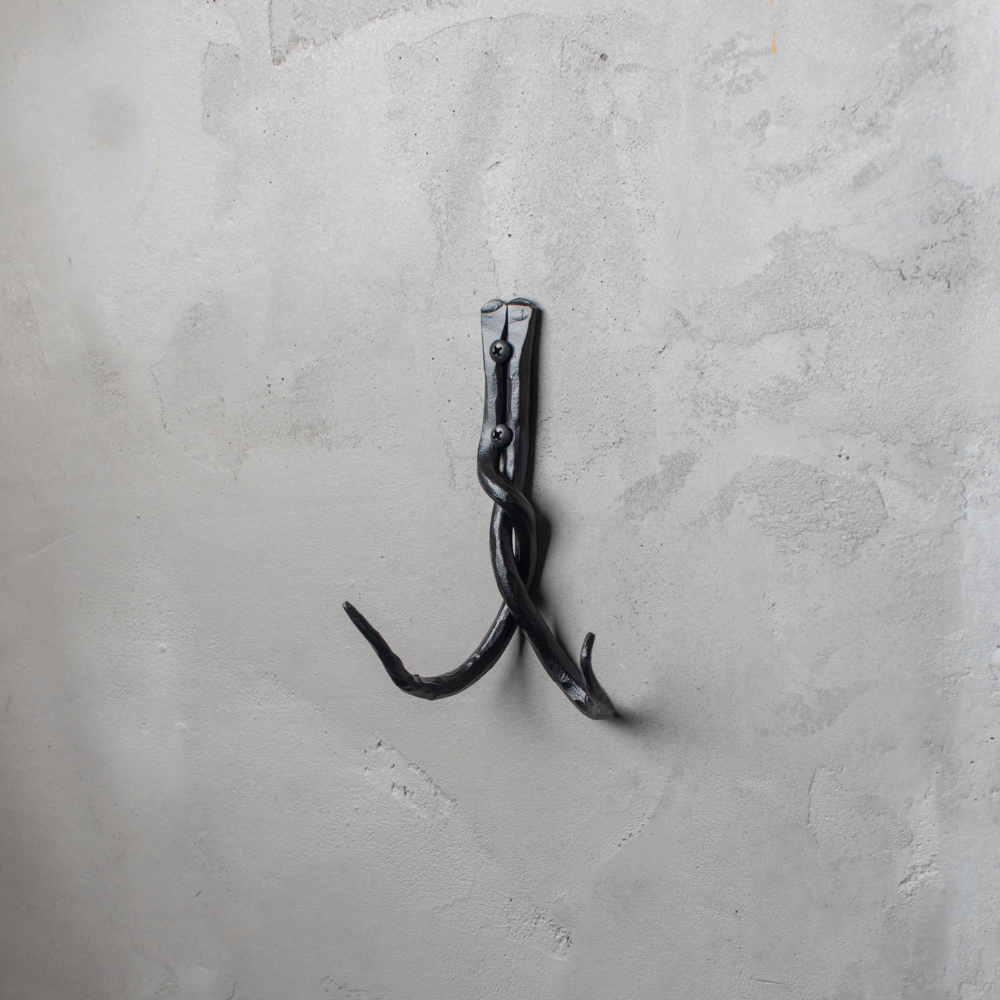 An Urban Forge Black River hand-forged iron double hook in a black finish. The hook is mounted on a gray wall.