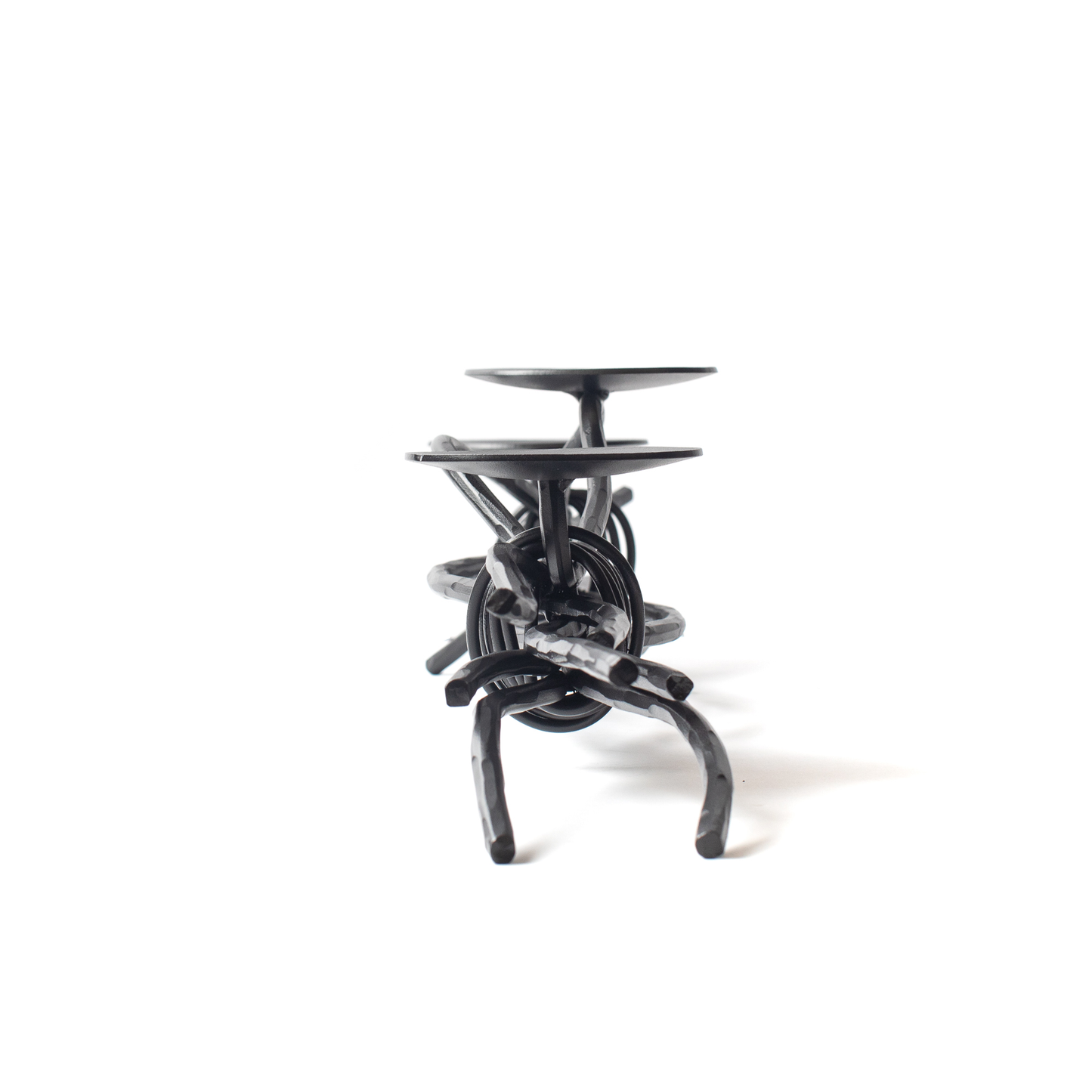 The Urban Forge Black River triple candle holder in a black finish. The candle holder is pictured against a white backdrop.
