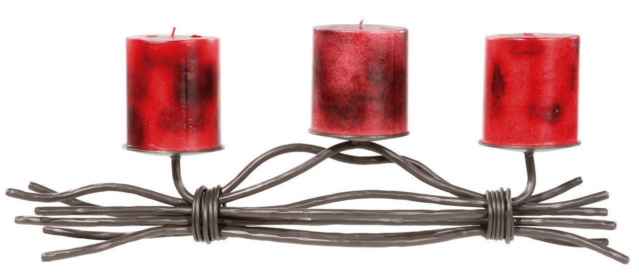 The Urban Forge Black River triple candle holder in a black finish. The candle holder has three red candles and is pictured against a white backdrop.