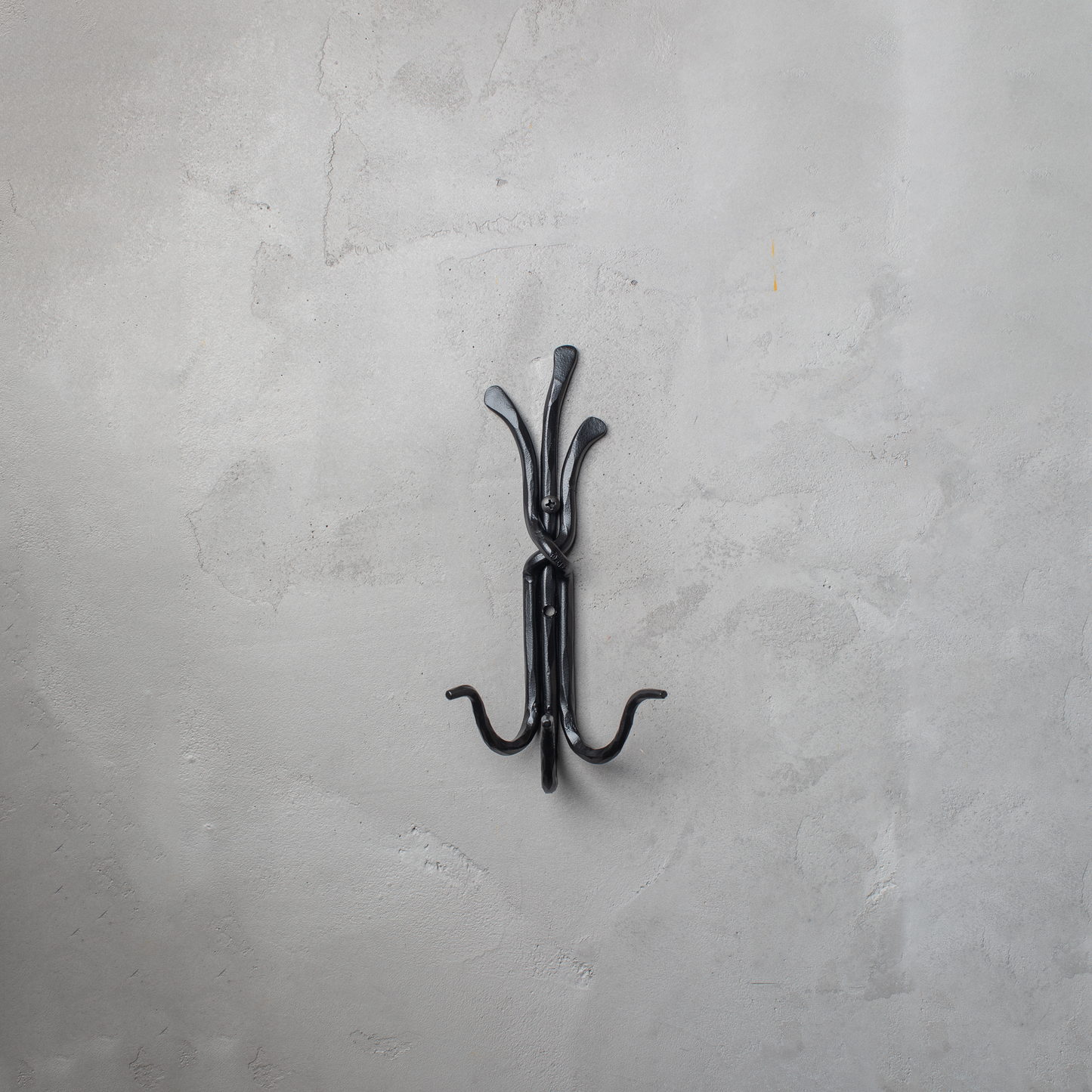 An Urban Forge Black River hand-forged iron triple hook in a black finish. The hook is mounted on a gray wall.
