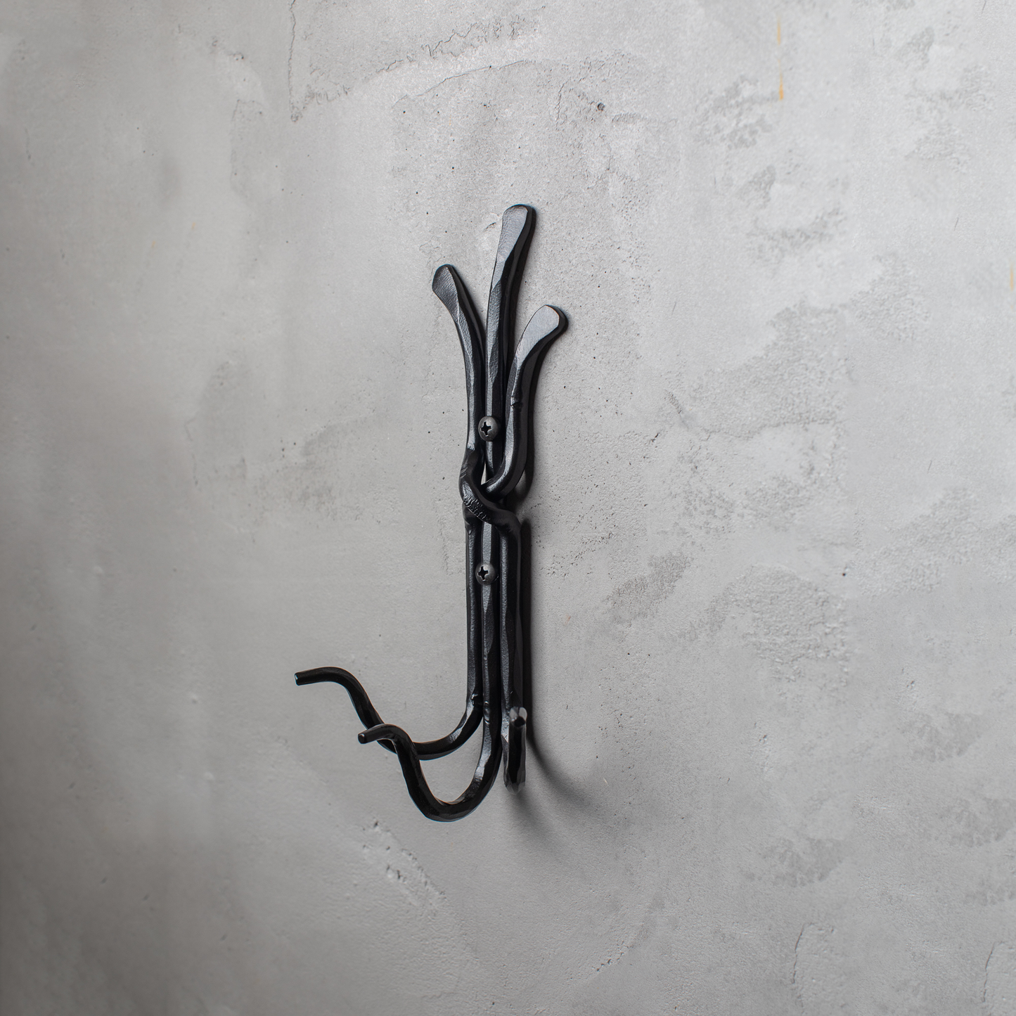 An Urban Forge Black River hand-forged iron triple hook in a black finish. The hook is mounted on a gray wall.