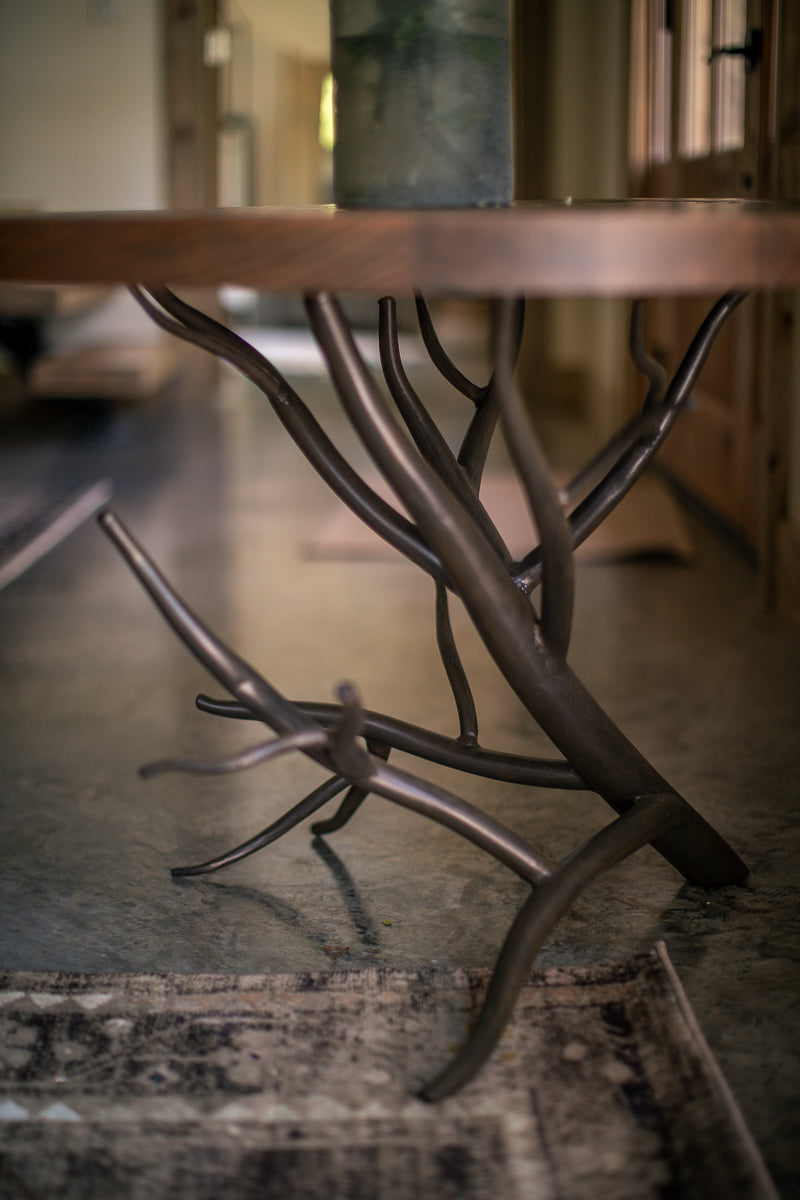 The Urban Forge Driftwood side table rests alongside a comfortable chair in a cozy living room.