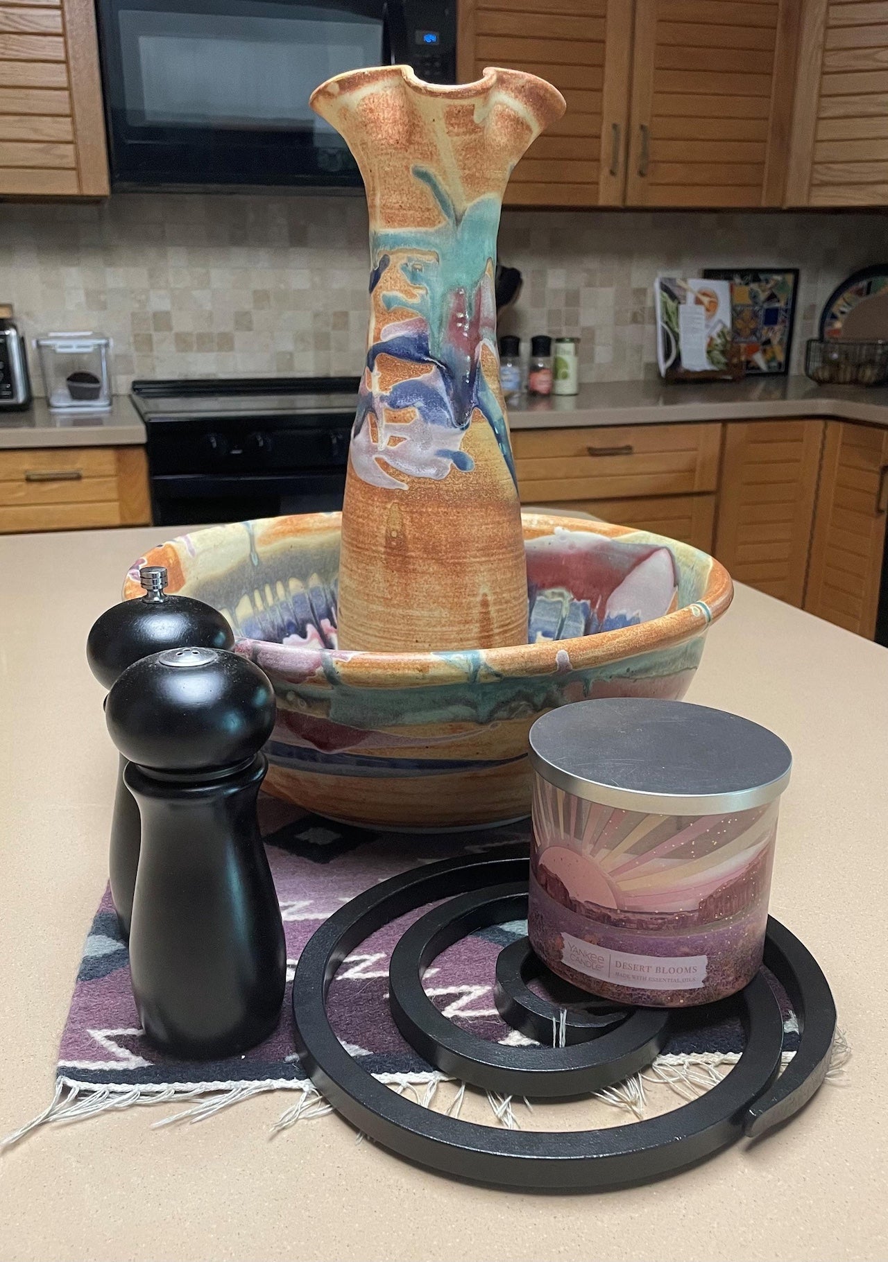 Ceramic bowl with an iron trivet and decorative elements on a kitchen counter.