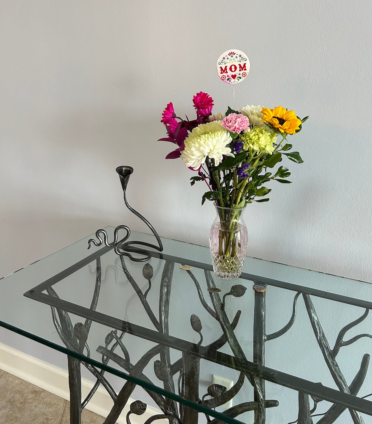 An Urban Forge Ivy single candle holder sitting on top a console table next to a vase full of flowers.