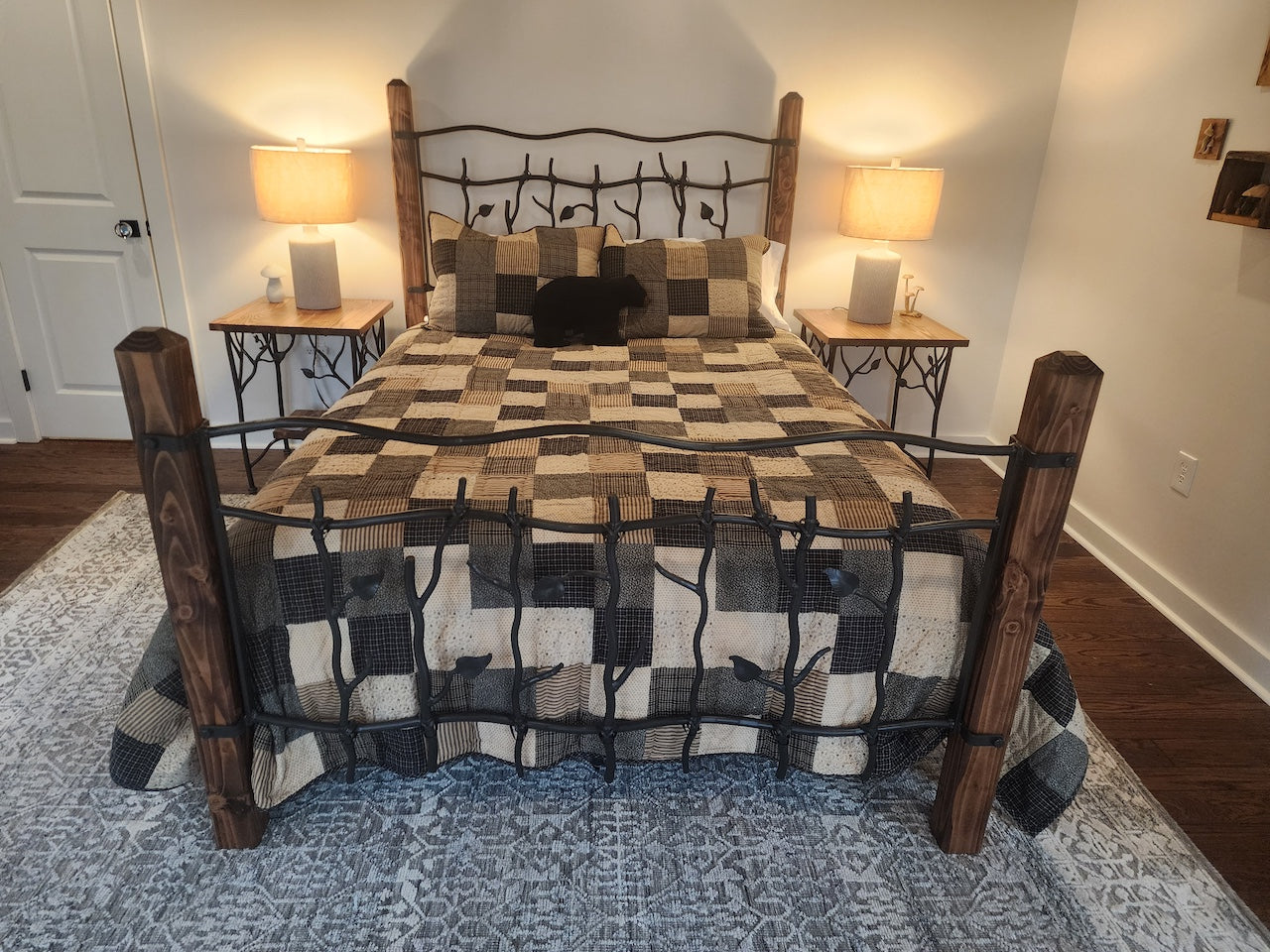 Bedroom with a bed featuring a checkered quilt and wooden and iron headboard, two lamps on nightstands.