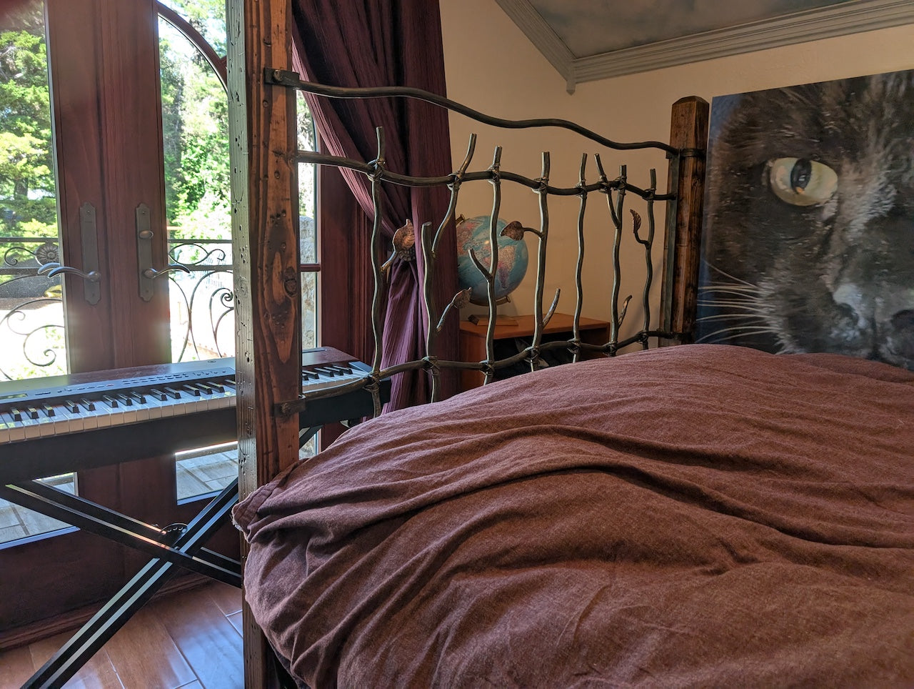 Bedroom with a bed featuring a decorative headboard and a large cat painting on the wall.