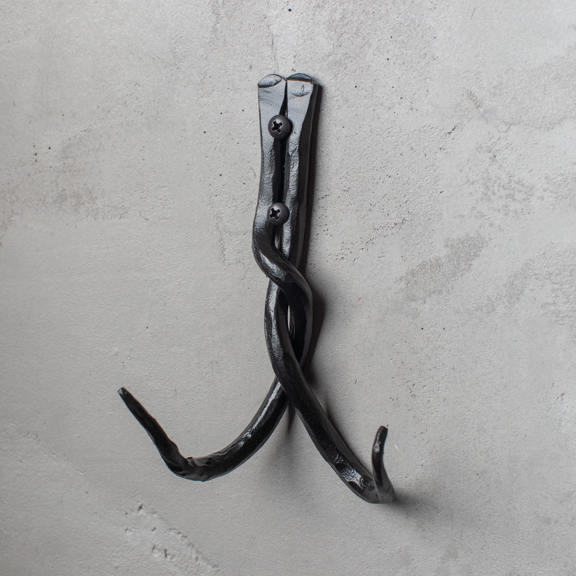 An Urban Forge Black River hand-forged iron double hook in a black finish. The hook is mounted on a gray wall.