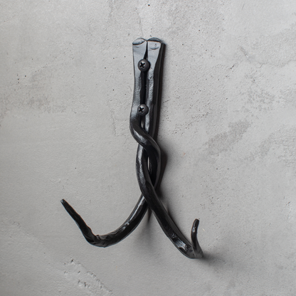 An Urban Forge Black River hand-forged iron double hook in a black finish. The hook is mounted on a gray wall.