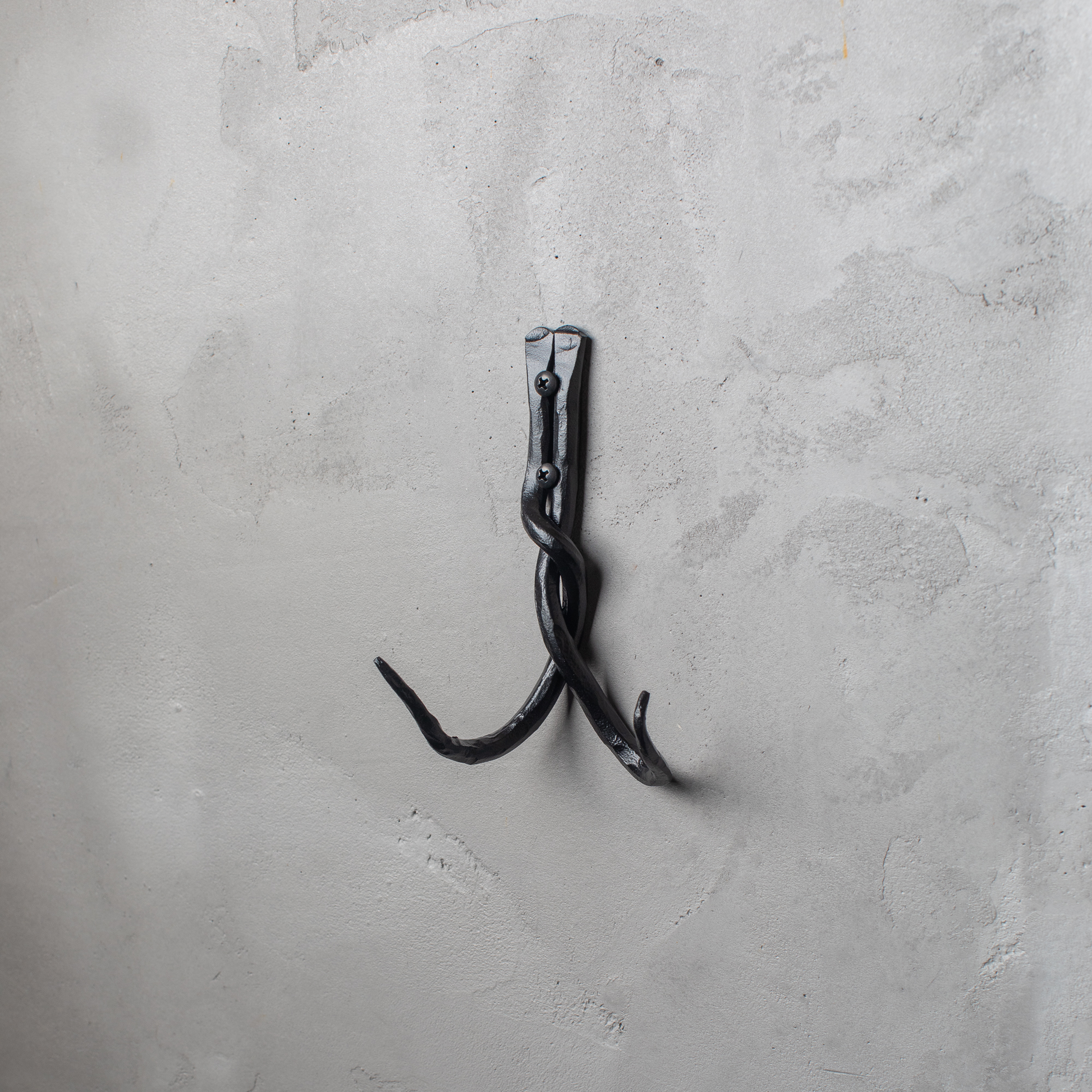 An Urban Forge Black River hand-forged iron double hook in a black finish. The hook is mounted on a gray wall.
