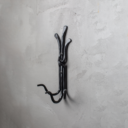 An Urban Forge Black River hand-forged iron triple hook in a black finish. The hook is mounted on a gray wall.