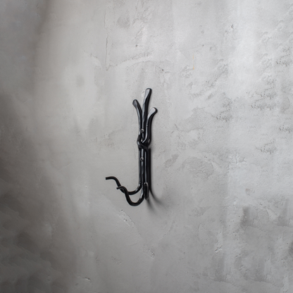 An Urban Forge Black River hand-forged iron triple hook in a black finish. The hook is mounted on a gray wall.