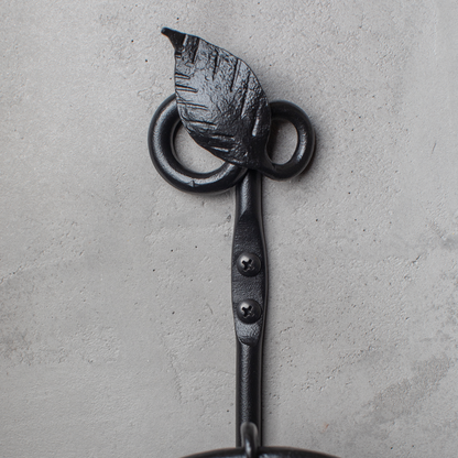 The Urban Forge Leaf towel ring in a black finish. The towel ring is mounted on a gray wall.