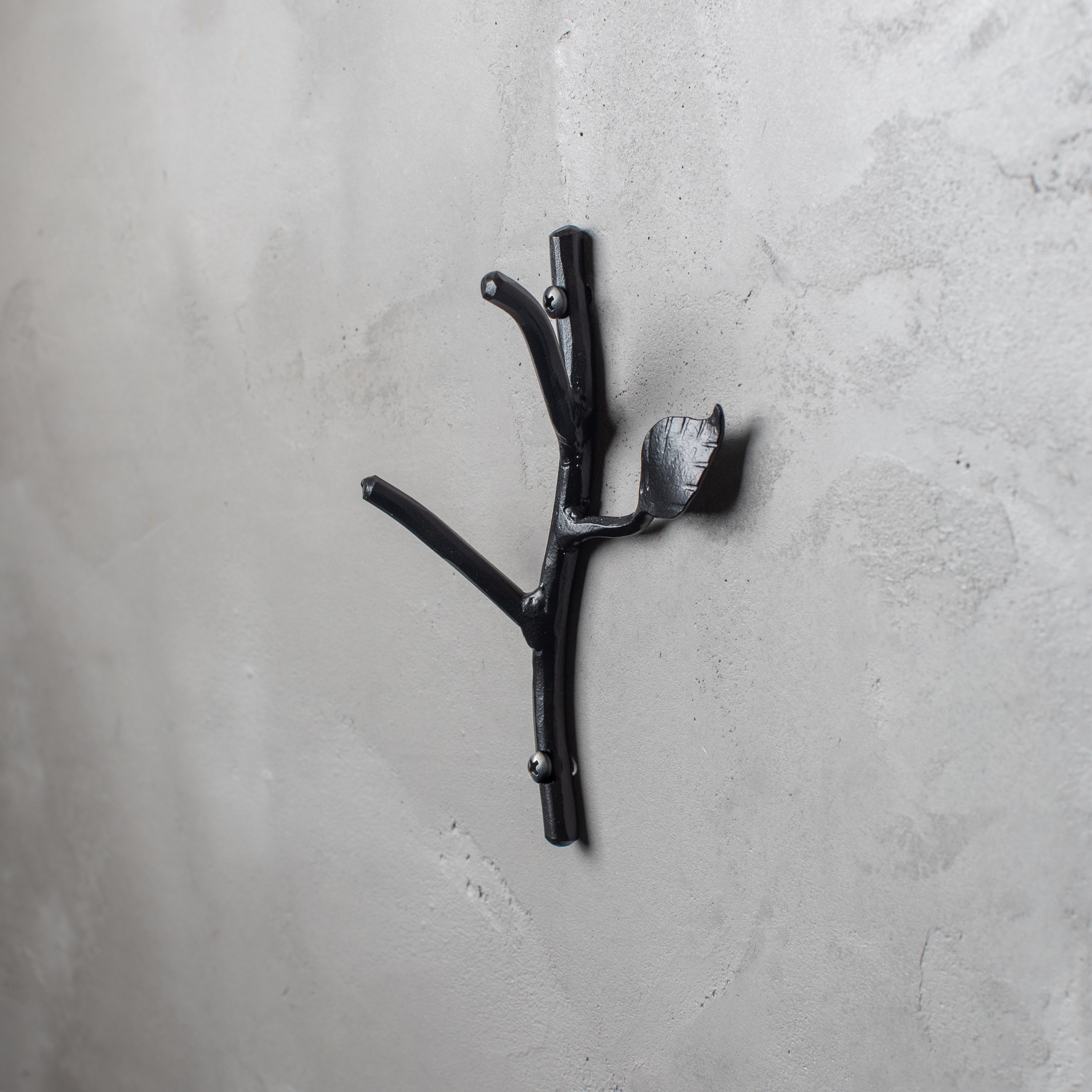 An Urban Forge Sylamore hand-forged iron double hook in a black finish. The hook is mounted on a gray wall.