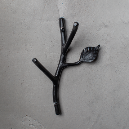 An Urban Forge Sylamore hand-forged iron double hook in a black finish. The hook is mounted on a gray wall.