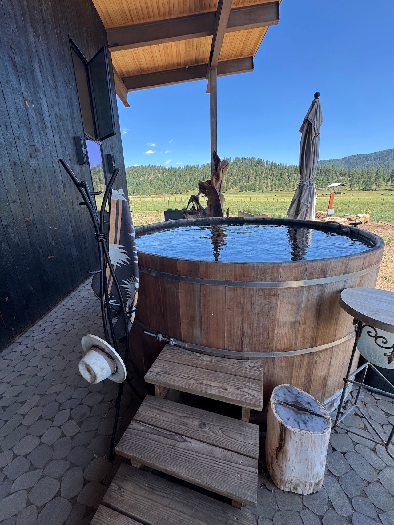 Wooden hot tub on a patio with a scenic background